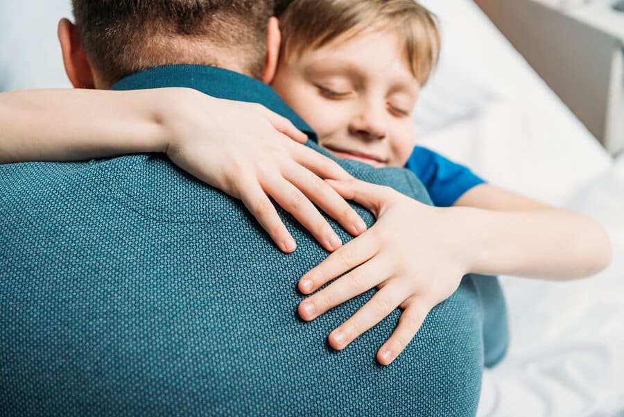 Portrait Of Smiling Little Son Hugging Father